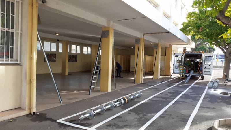 Installation de rideaux métalliques galvanisés lames micro-perforées dans une école pour fermeture d'un préau